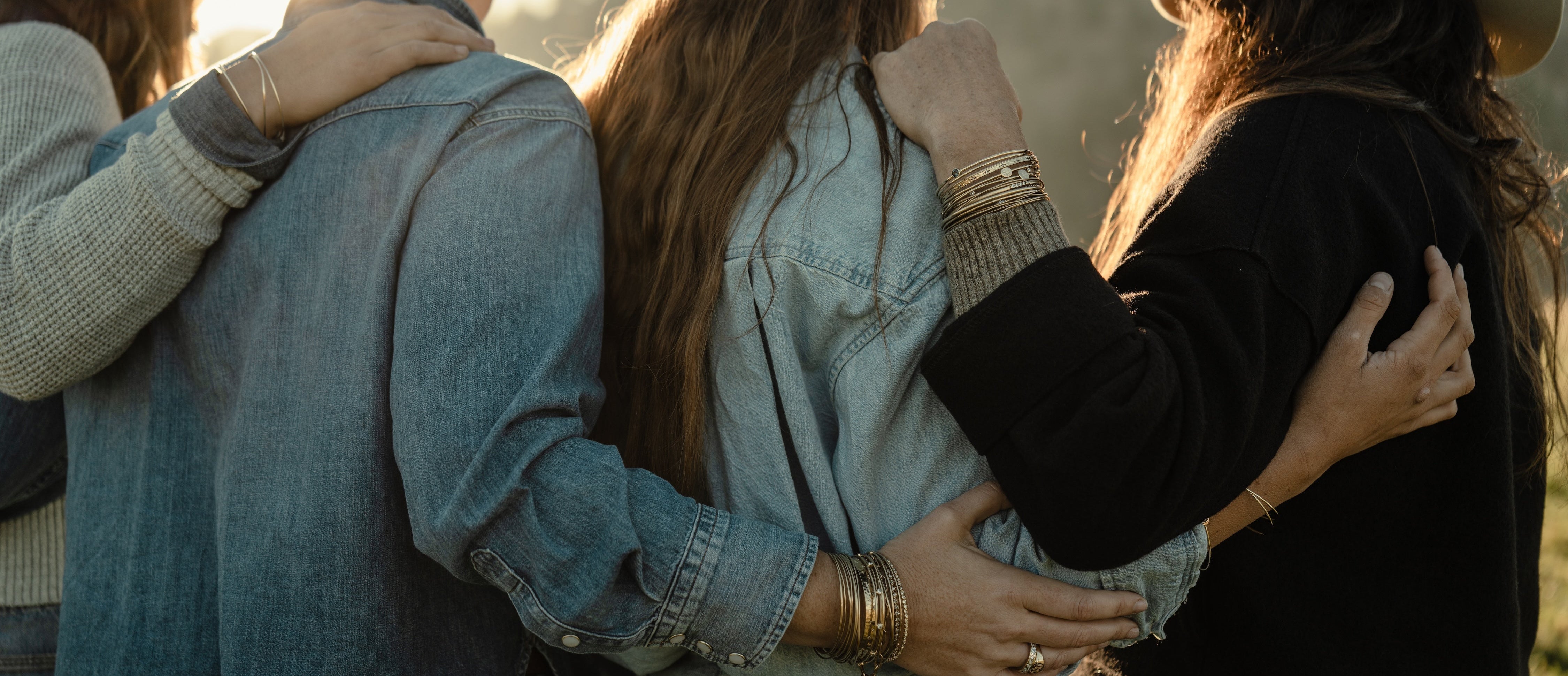 Group of people embracing in a field with a warm, golden light