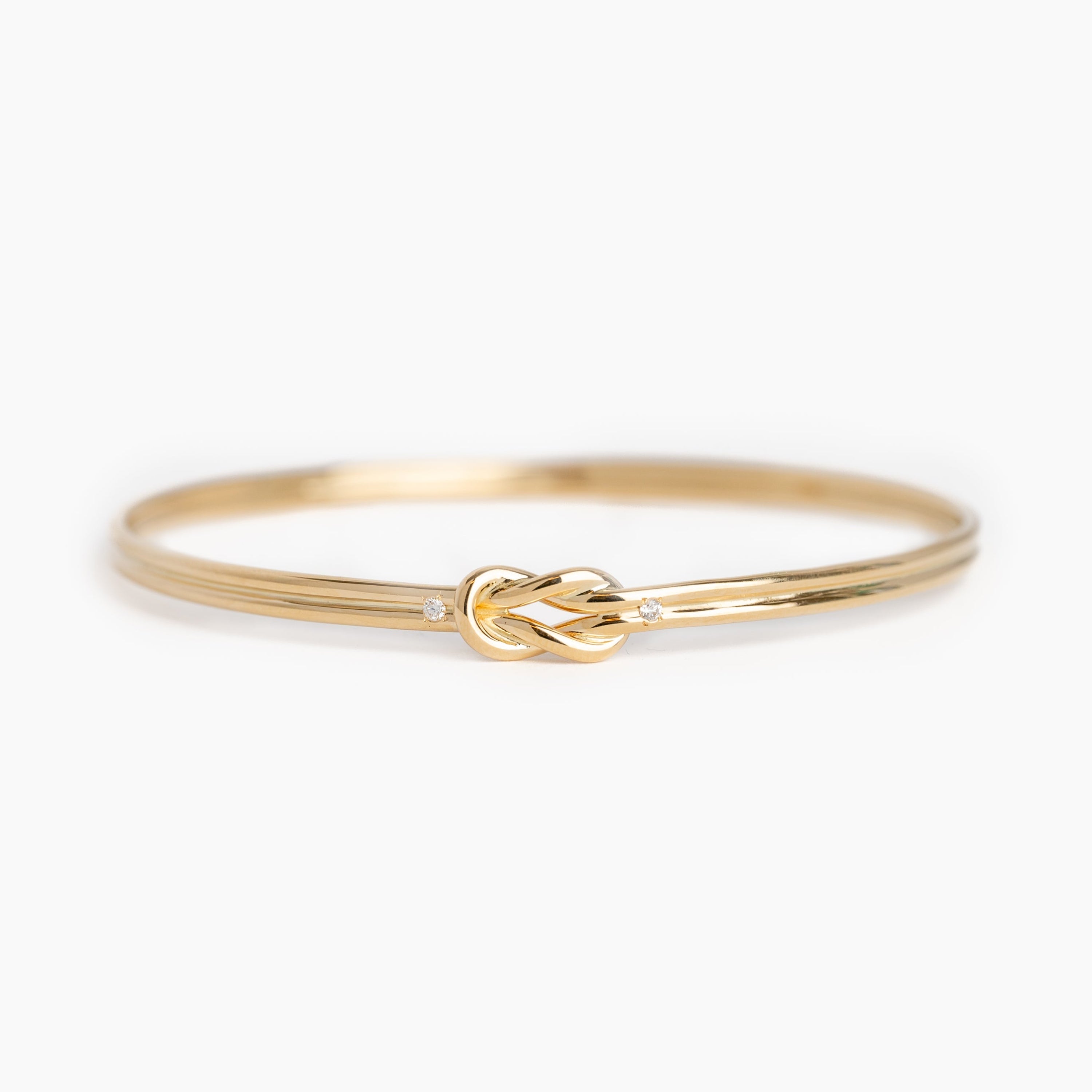 Gold bracelet with a knot design on a white background