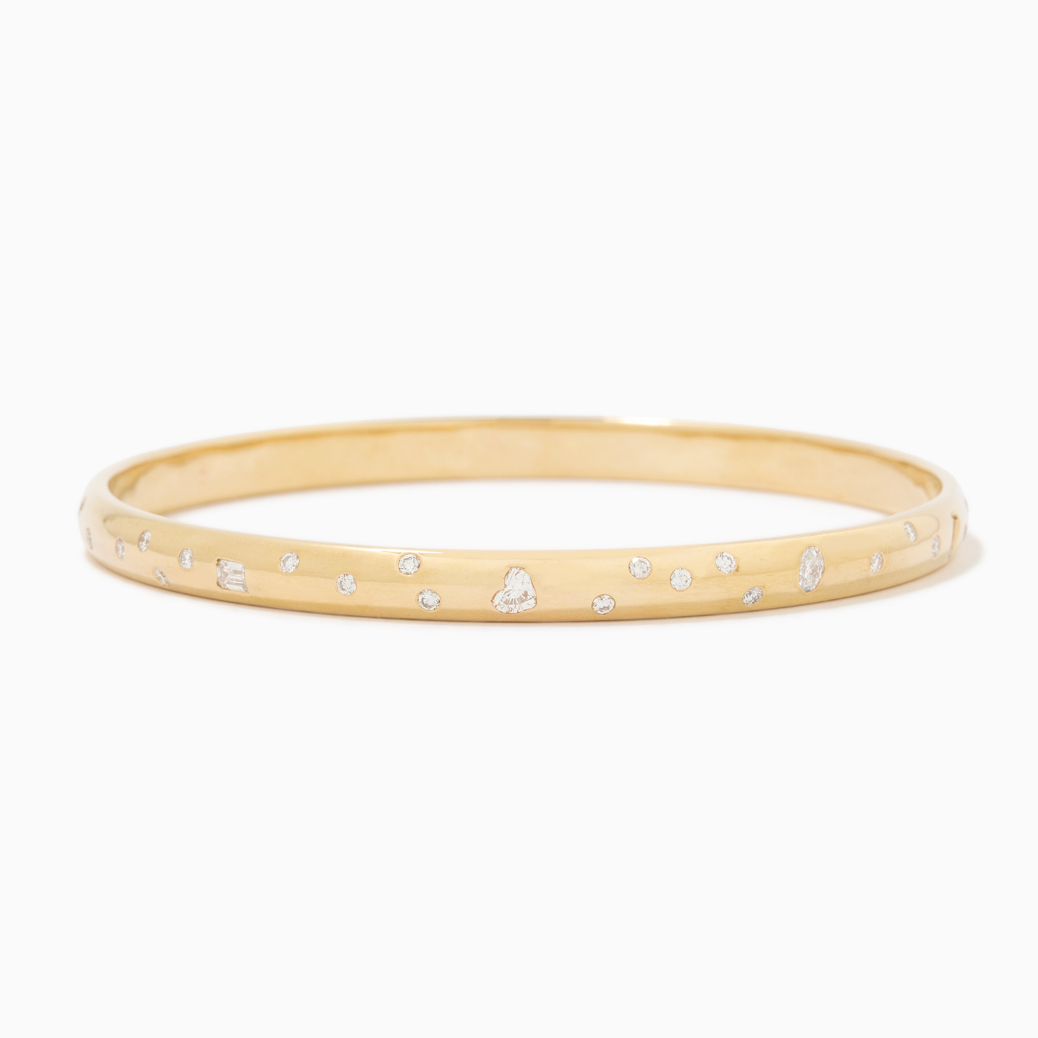 A thin yellow gold bangle bracelet with small, evenly spaced clear gemstones set along the outer band, shown against a plain white background.