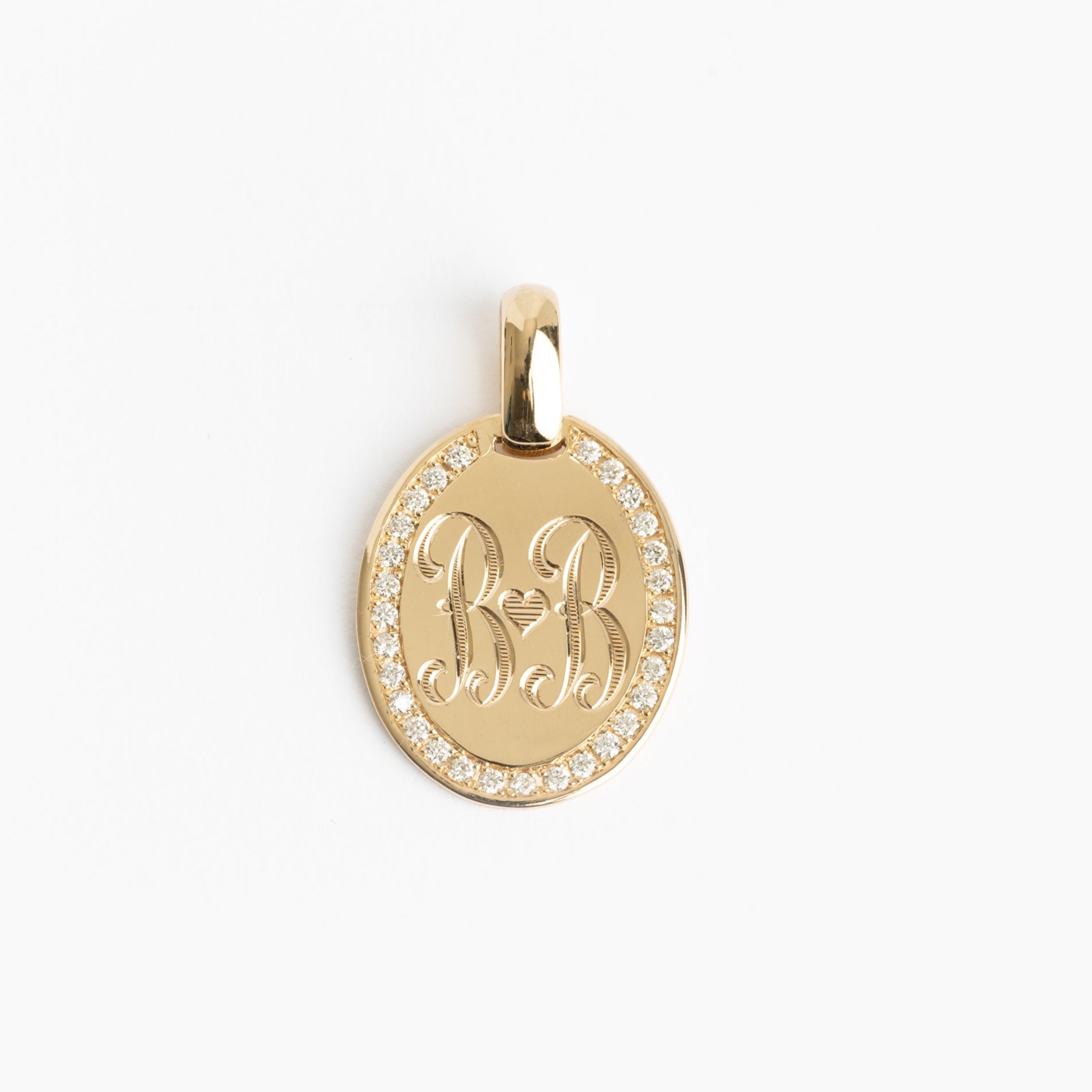 Gold pendant with engraved initials on a white background
