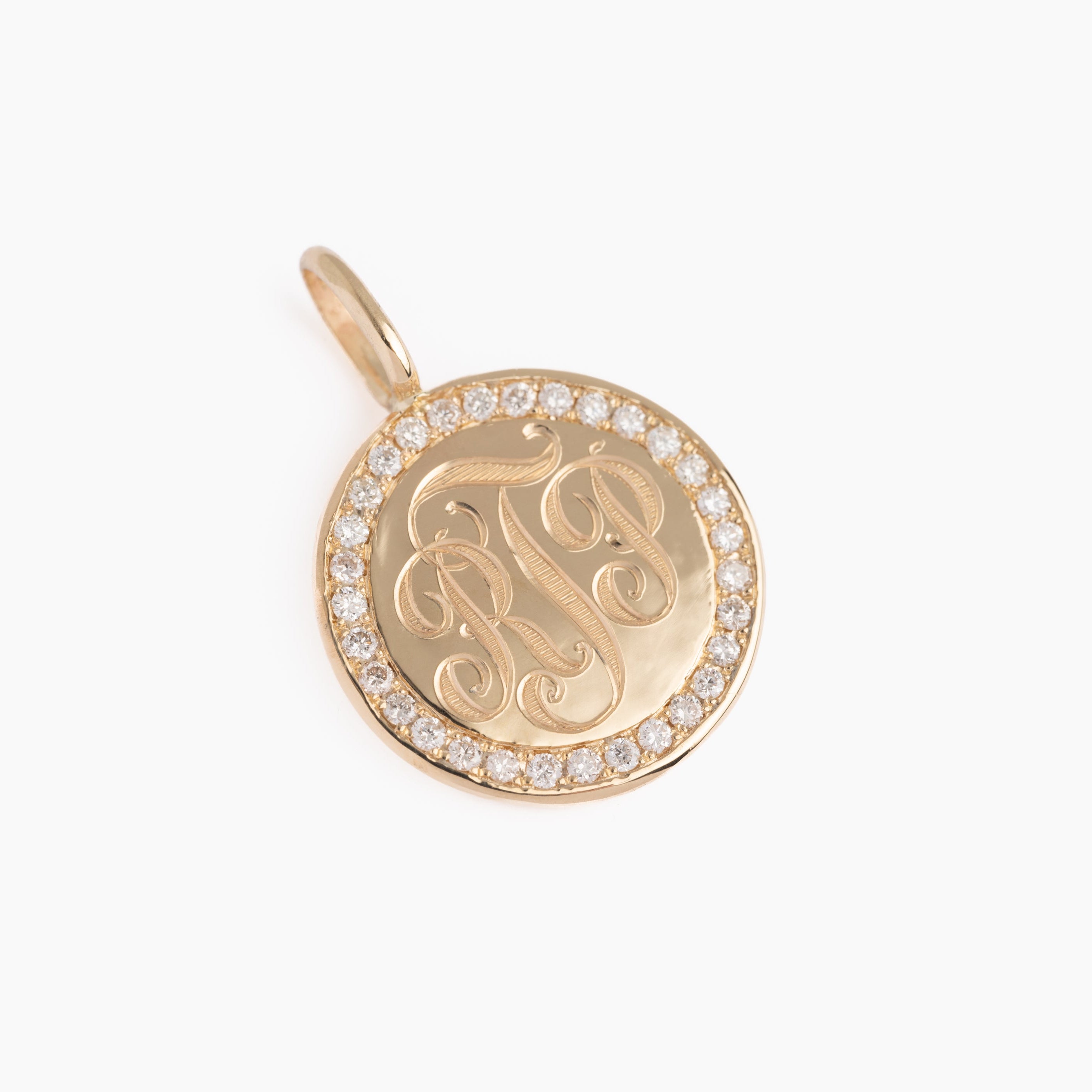 Gold pendant with monogram design and clear stones on a white background