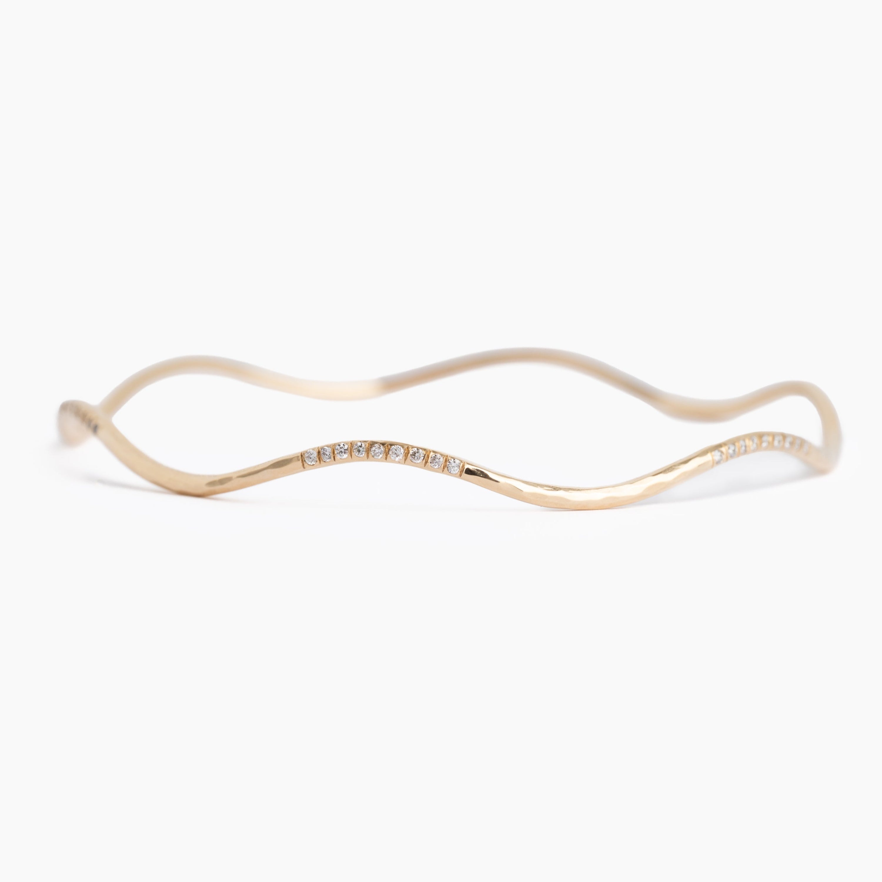 Gold bracelet with wavy design on a white background