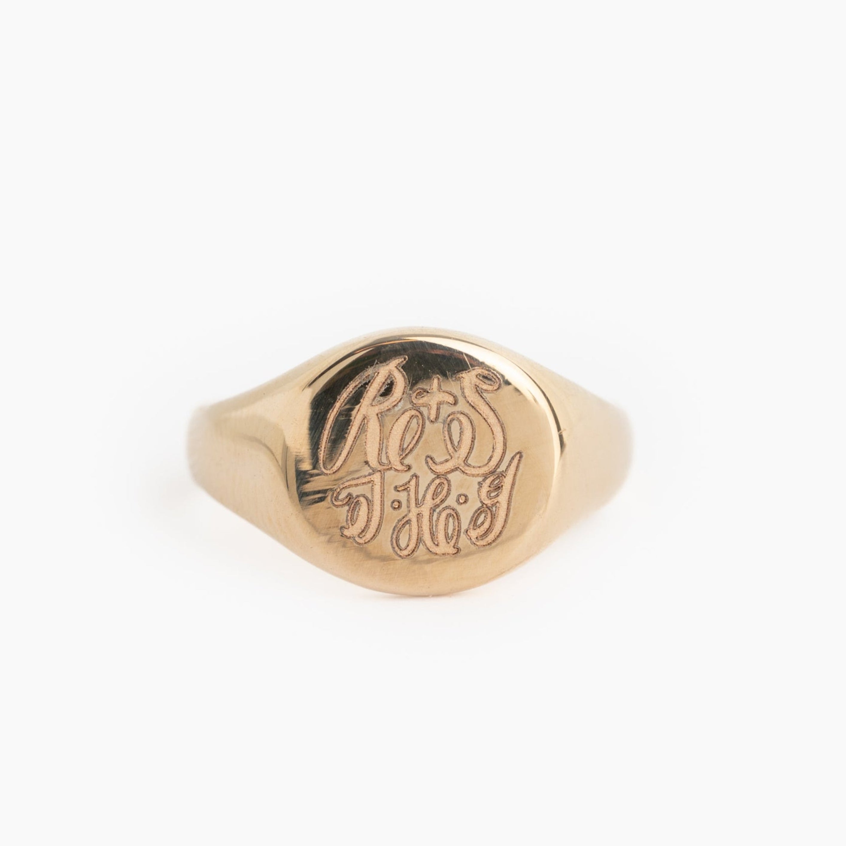 Gold signet ring with engraved design on a white background